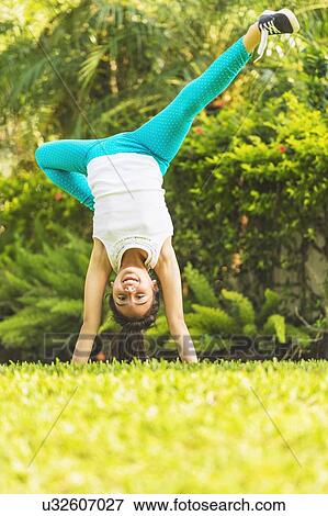 Stock Photo - girl (8-9) doing cartwheel on front yard. Fotosearch