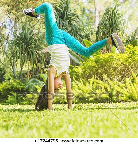 Stock Photography - girl (8-9) doing cartwheel on front yard. Fotosearch