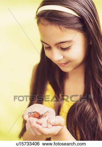 Stock Photograph - girl ( 8-9) holding butterfly in hands. Fotosearch