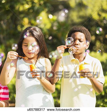 Girls( 4-5, 8-9) and boy (6-7) blowing soap bubble View Large Photo Image Stock Photo - Girls( 4-5, 8-9) and boy (6-7) blowing soap bubble. Fotosearch