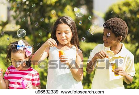 Girls( 4-5, 8-9) and boy (6-7) blowing soap bubble View Large Photo Image Stock Photo - Girls( 4-5, 8-9) and boy (6-7) blowing soap bubble. Fotosearch