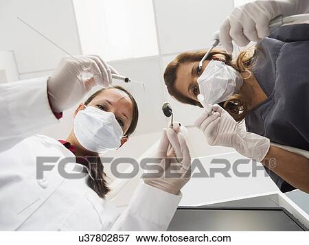 Stock Photo - Lowe angle view of dentist and assistant. Fotosearch
