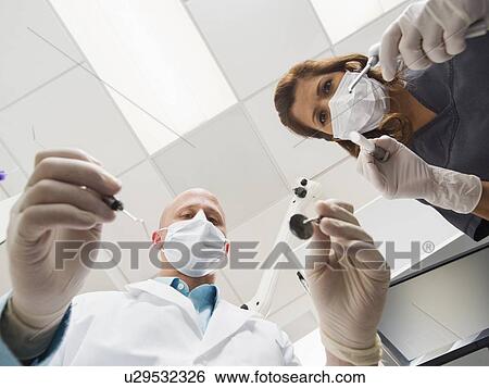 Stock Photograph - Lowe angle view of dentist and assistant. Fotosearch