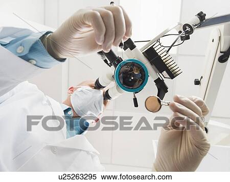 Lowe angle view of dentist using microscope View Large Photo Image Stock Photography - Lowe angle view of dentist using microscope. Fotosearch