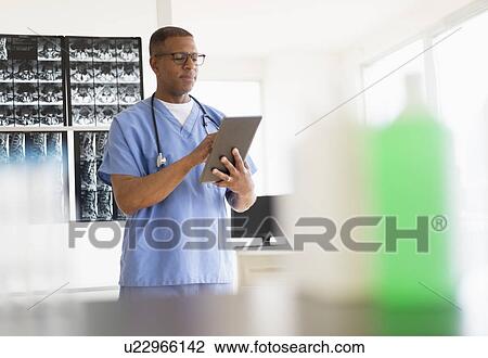 Stock Image - Male doctor in hospital using digital tablet. Fotosearch