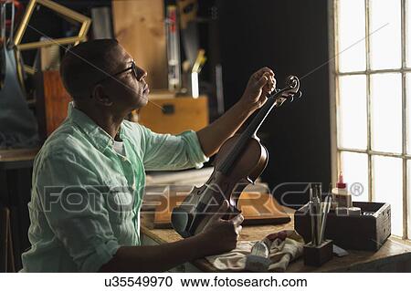 Mature man fixing violin in his workshop View Large Photo Image Stock Image - Mature man fixing violin in his workshop. Fotosearch