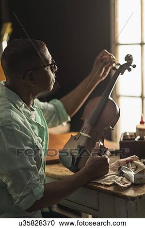 Mature man fixing violin in his workshop View Large Photo Image Stock Image - Mature man fixing violin in his workshop. Fotosearch
