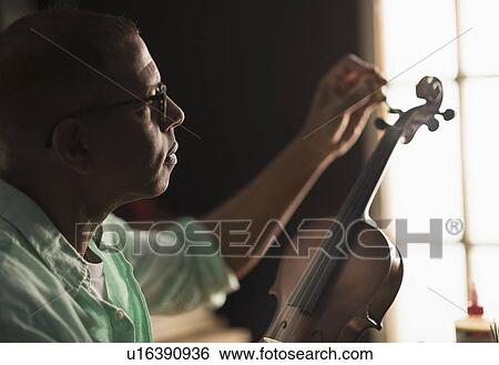 Mature man fixing violin in his workshop View Large Photo Image Stock Photograph - Mature man fixing violin in his workshop. Fotosearch
