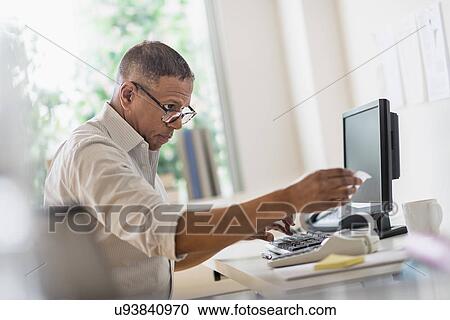 Stock Image - Mature man working in home office. Fotosearch