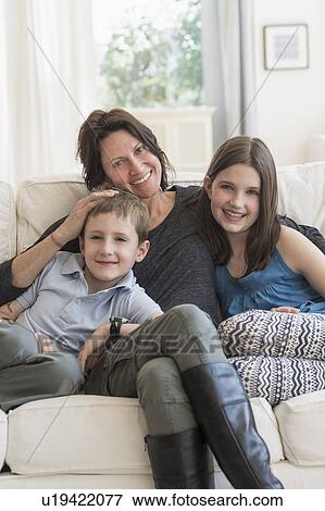 Mother and kids(8-9, 10-11) sitting on sofa View Large Photo Image Stock Photo - Mother and kids(8-9, 10-11) sitting on sofa. Fotosearch