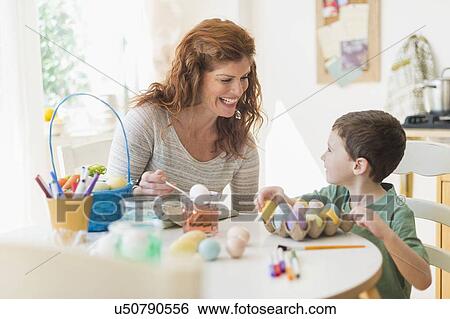Stock Photograph - Mother and son (6-7) painting Easter eggs. Fotosearch