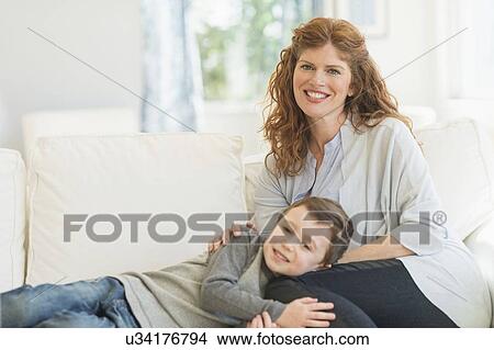 Picture - Mother and son (6-7) relaxing on sofa. Fotosearch