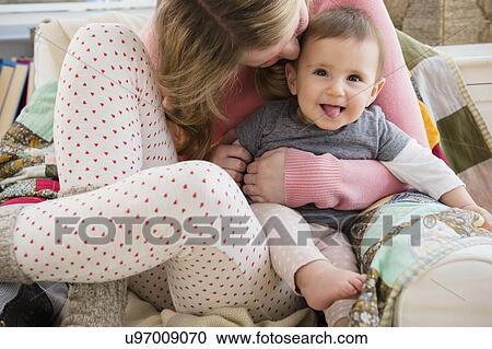 Stock Image - Mother embracing baby girl (6-11 moths). Fotosearch