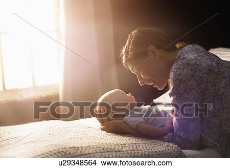 Mother holding baby boy (2-5 months) in bedroom View Large Photo Image Picture - Mother holding baby boy (2-5 months) in bedroom. Fotosearch