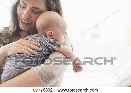 Stock Image - Mother holding baby boy (2-5 months) on her arm. Fotosearch