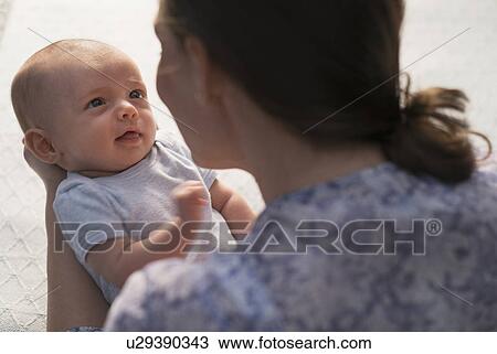 Stock Image - Mother holding baby boy (2-5 months). Fotosearch