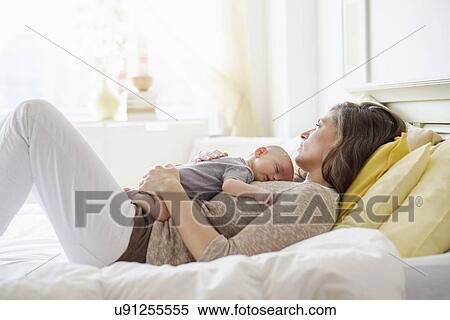 Stock Photography - Mother lying in bed with baby boy (2-5 months). Fotosearch