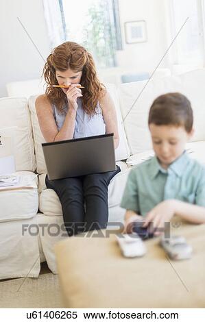 Mother using laptop, son (6-7) playing with toy cars View Large Photo Image Stock Photography - Mother using laptop, son (6-7) playing with toy cars. Fotosearch