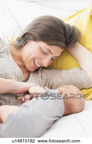 Mother with baby boy (2-5 months) lying on bed View Large Photo Image Stock Image - Mother with baby boy (2-5 months) lying on bed. Fotosearch