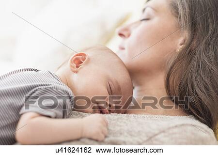 Stock Image - Mother with baby boy (2-5 months) taking nap together. Fotosearch