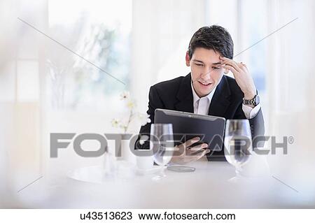 Stock Image - Portrait of business man using digital tablet in restaurant. Fotosearch