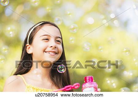 Picture - Portrait of girl (8-9) blowing bubbles. Fotosearch