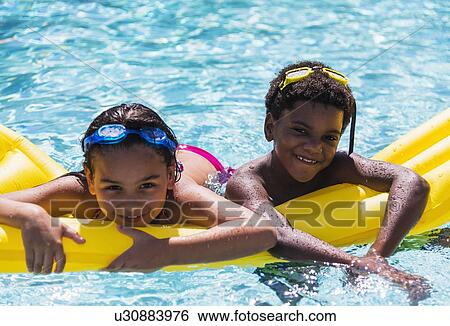 Stock Photograph - Portrait of kids( 6-7, 8-9) with pool raft. Fotosearch