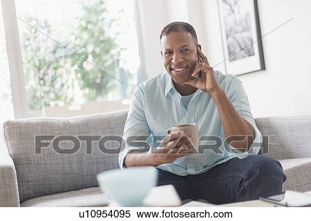 Portrait of man sitting on sofa at home View Large Photo Image Stock Photography - Portrait of man sitting on sofa at home. Fotosearch