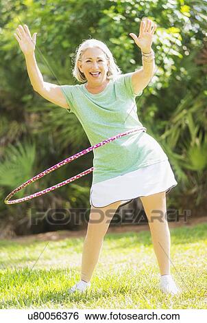 Portrait of senior woman spinning hula hoop View Large Photo Image Stock Photograph - Portrait of senior woman spinning hula hoop. Fotosearch