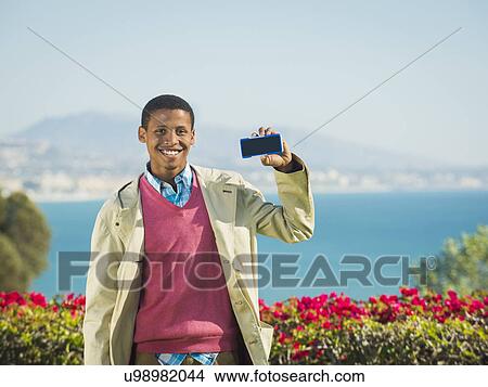 Portrait of smiling man holding smartphone View Large Photo Image Picture - Portrait of smiling man holding smartphone. Fotosearch