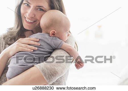 Portrait of smiling mother holding baby boy (2-5 months) on her arm View Large Photo Image Stock Image - Portrait of smiling mother holding baby boy (2-5 months) on her arm. Fotosearch