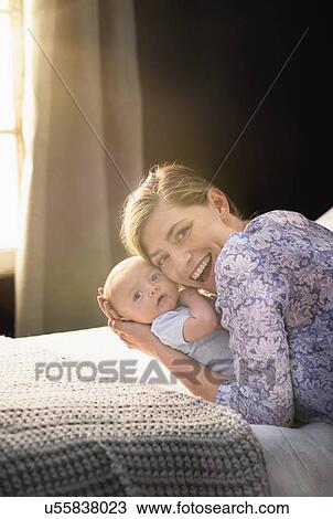 Portrait of smiling Mother holding baby boy (2-5 months) in bedroom View Large Photo Image Stock Image - Portrait of smiling Mother holding baby boy (2-5 months) in bedroom. Fotosearch