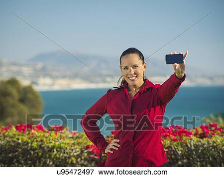 Stock Photo - Portrait of smiling woman holding smartphone. Fotosearch