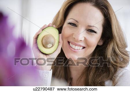 Stock Photo - Portrait of woman holding avocado. Fotosearch