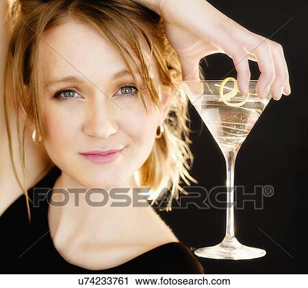 Stock Image - Portrait of woman holding martini glass. Fotosearch