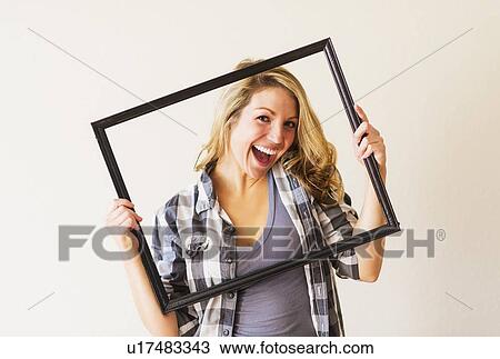 Stock Image - Portrait of woman holding picture frame. Fotosearch
