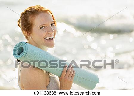Stock Photo - Portrait of woman holding yoga mat. Fotosearch