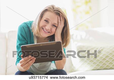 Portrait of woman on sofa holding digital tablet View Large Photo Image Picture - Portrait of woman on sofa holding digital tablet. Fotosearch