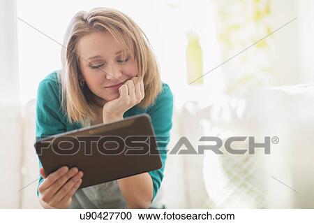Portrait of woman on sofa using digital tablet View Large Photo Image Stock Image - Portrait of woman on sofa using digital tablet. Fotosearch