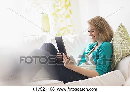Stock Photo - Portrait of woman on sofa using digital tablet. Fotosearch