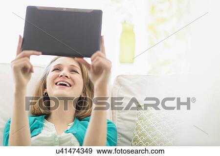 Portrait of woman on sofa using digital tablet View Large Photo Image Stock Photo - Portrait of woman on sofa using digital tablet. Fotosearch