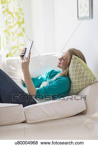 Stock Photo - Portrait of woman on sofa using digital tablet. Fotosearch