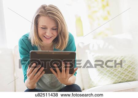 Portrait of woman on sofa using digital tablet View Large Photo Image Stock Photo - Portrait of woman on sofa using digital tablet. Fotosearch