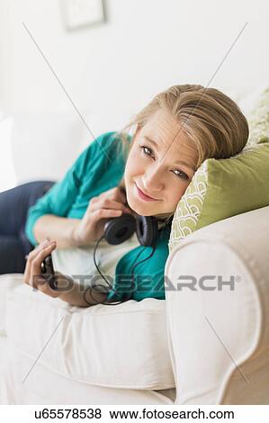 Stock Photo - Portrait of woman on sofa with smart phone. Fotosearch