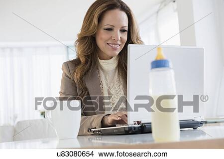 Picture - Portrait of working mother at laptop. Fotosearch