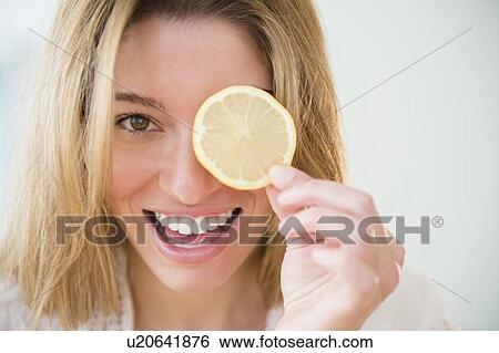 Portrait of young woman holding lemon slice View Large Photo Image Stock Photograph - Portrait of young woman holding lemon slice. Fotosearch