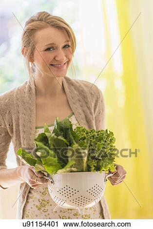 Portrait of young woman holding lettuce in colander View Large Photo Image Stock Image - Portrait of young woman holding lettuce in colander. Fotosearch