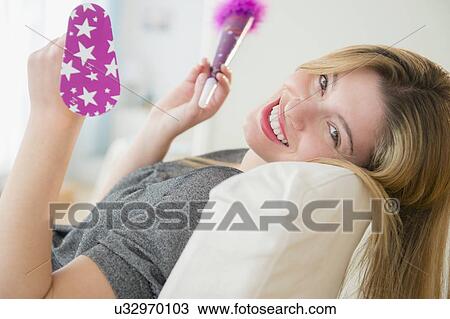 Stock Image - Portrait of young woman holding noisemakers. Fotosearch