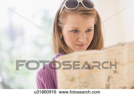 Stock Photograph - Portrait of young woman looking at map. Fotosearch