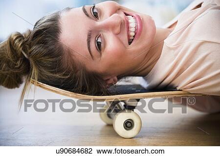 Portrait of young woman lying down on skateboard View Large Photo Image Stock Image - Portrait of young woman lying down on skateboard. Fotosearch